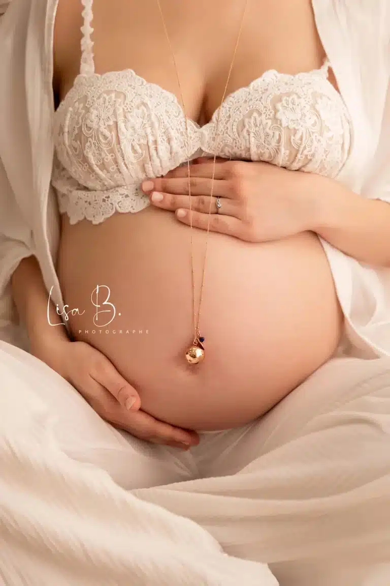 Détail des mains sur le ventre pendant séance grossesse en studio près de Chartres